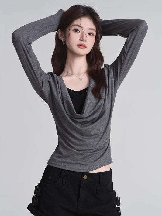 Model wearing a grey long-sleeved top with a draped neckline and a black underlayer.