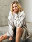 Woman wearing a white and gray faux fur coat and black shorts