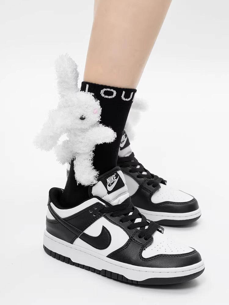 Close-up of black ankle socks with white 3D plush bunny embellishments and white sneakers