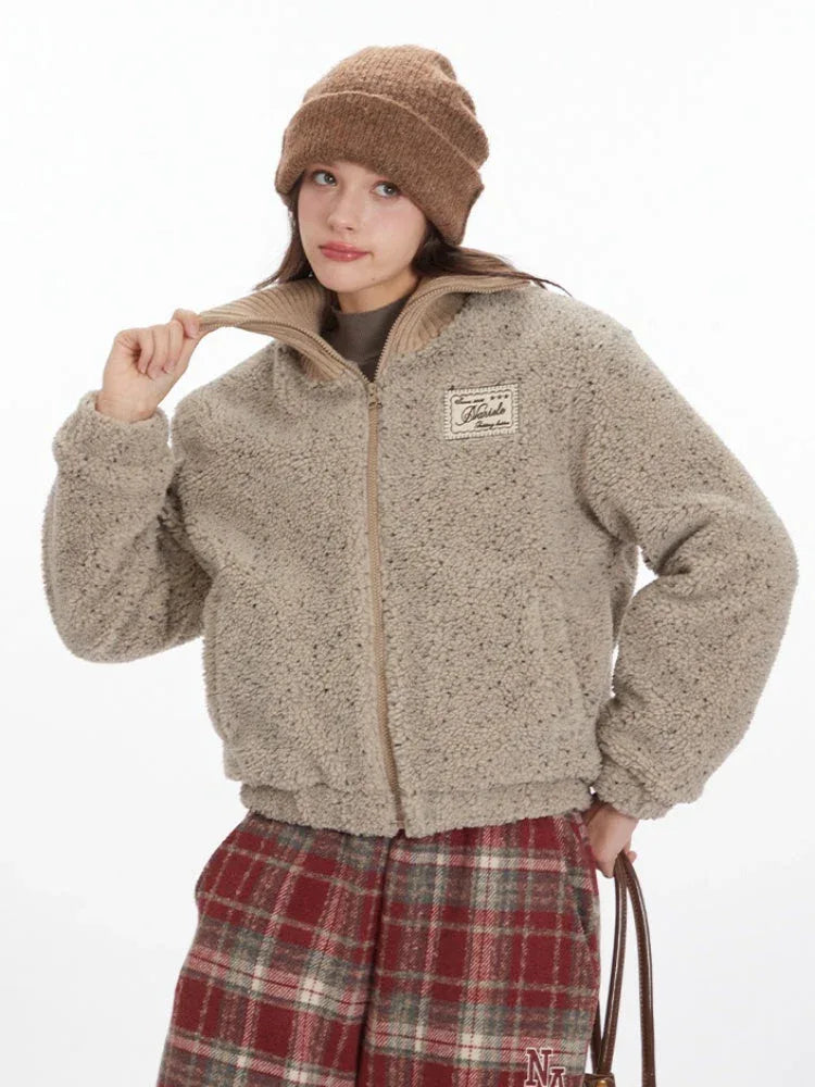 Close-up of a model adjusting the collar of a beige fuzzy bomber jacket.
