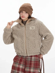 Close-up of a model adjusting the collar of a beige fuzzy bomber jacket.