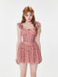 Woman wearing a red and white gingham print dress with ruffled sleeves and a cinched waist.