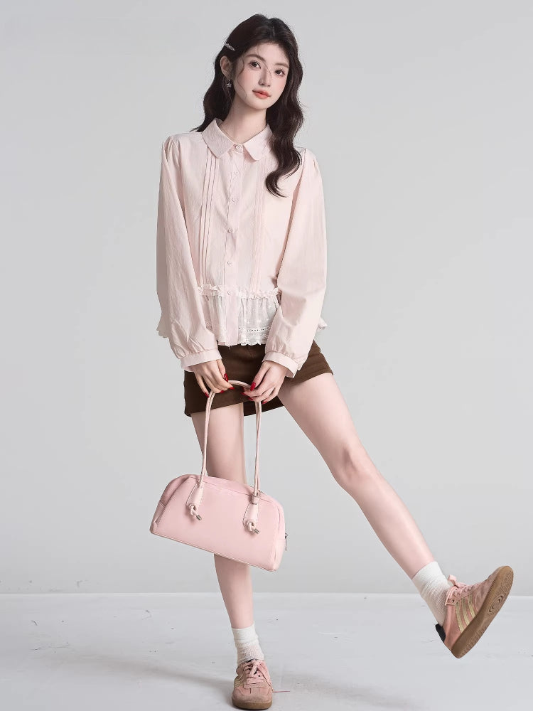 Full body shot of a woman wearing a light pink ruffled peplum blouse with a Peter Pan collar and lace trim, dark brown shorts, white socks, and pink sneakers, holding a pink handbag.
