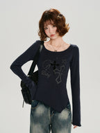 Close-up of the graphic print on the dark blue long-sleeve top, featuring crosses and stars.