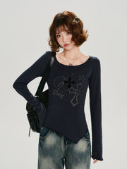 Close-up of the graphic print on the dark blue long-sleeve top, featuring crosses and stars.