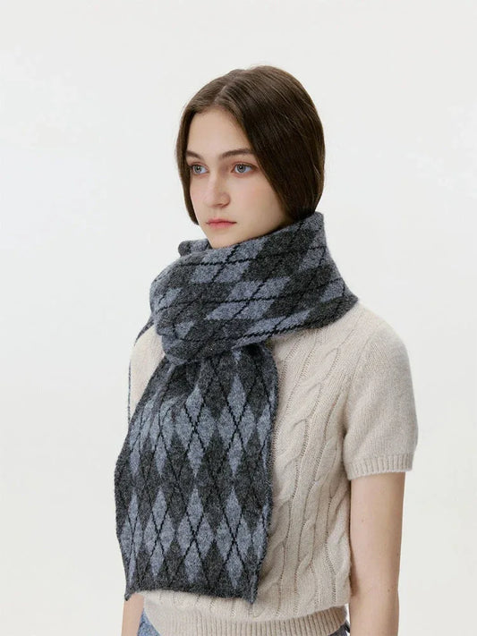 Close-up of a woman wearing a cream cable-knit sweater and a grey and black argyle scarf