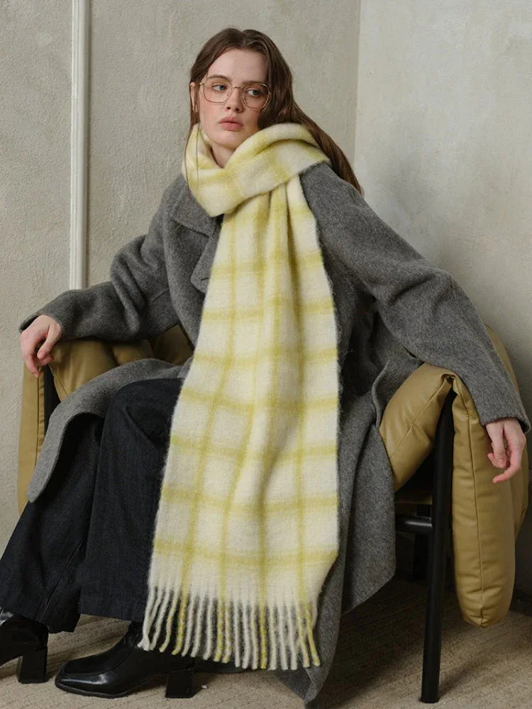 woman sitting in a chair wearing a grey coat and a yellow plaid scarf