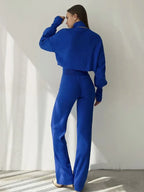 Back view of a woman wearing a blue knit two-piece set, highlighting the silhouette of the cropped sweater and pants.