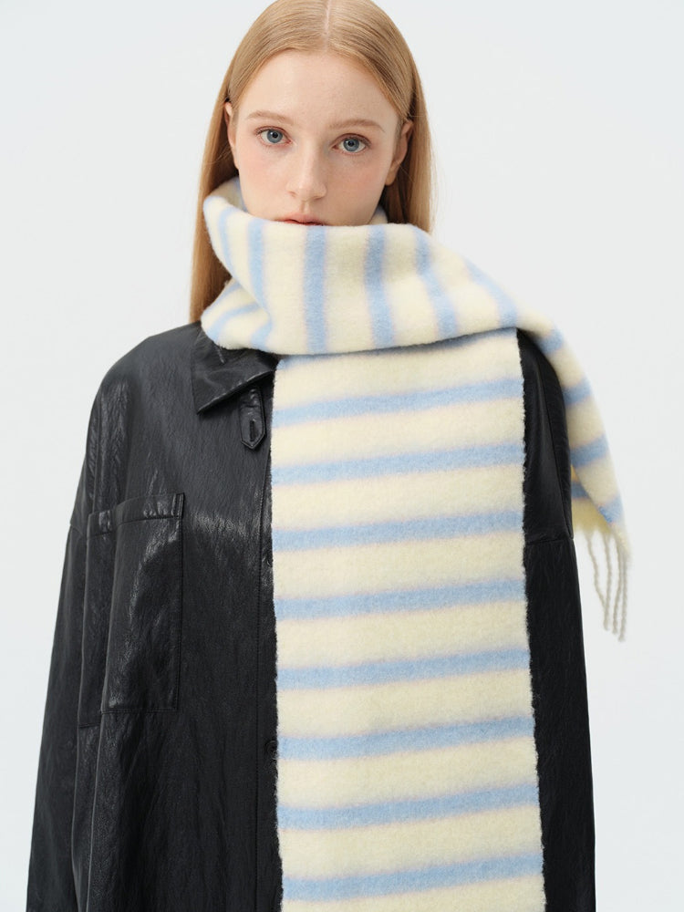 close-up of a model wearing a light yellow and blue striped scarf around her neck