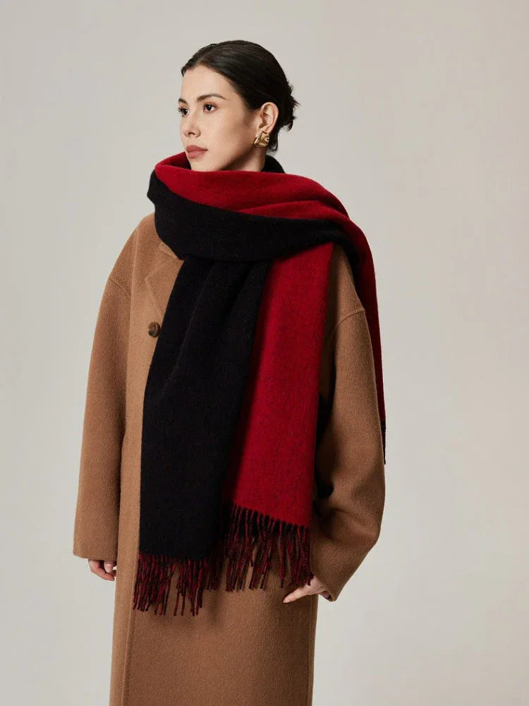 Woman wearing a camel coat and a red and black color-blocked scarf with fringe