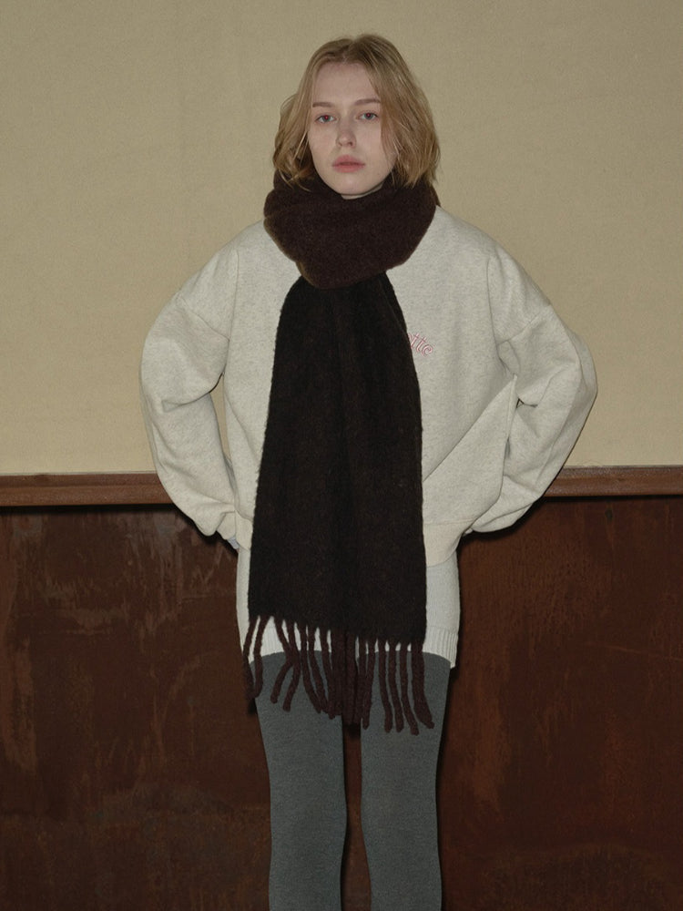 A young person wearing a cream-colored crew neck sweatshirt with a dark brown fringed scarf. Main image