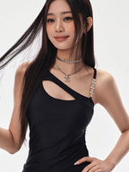 Close-up of a woman's upper body wearing a black asymmetrical cutout dress with layered necklaces.