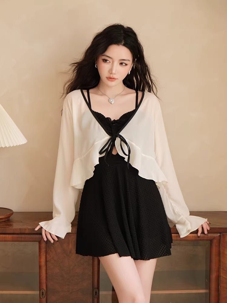 Woman wearing a black one-piece swimsuit with a white sheer cover-up