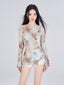 Woman wearing a tie-dye print mesh overlay long sleeve top and matching shorts