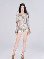 Woman in a tie-dye print mesh overlay top and shorts, standing