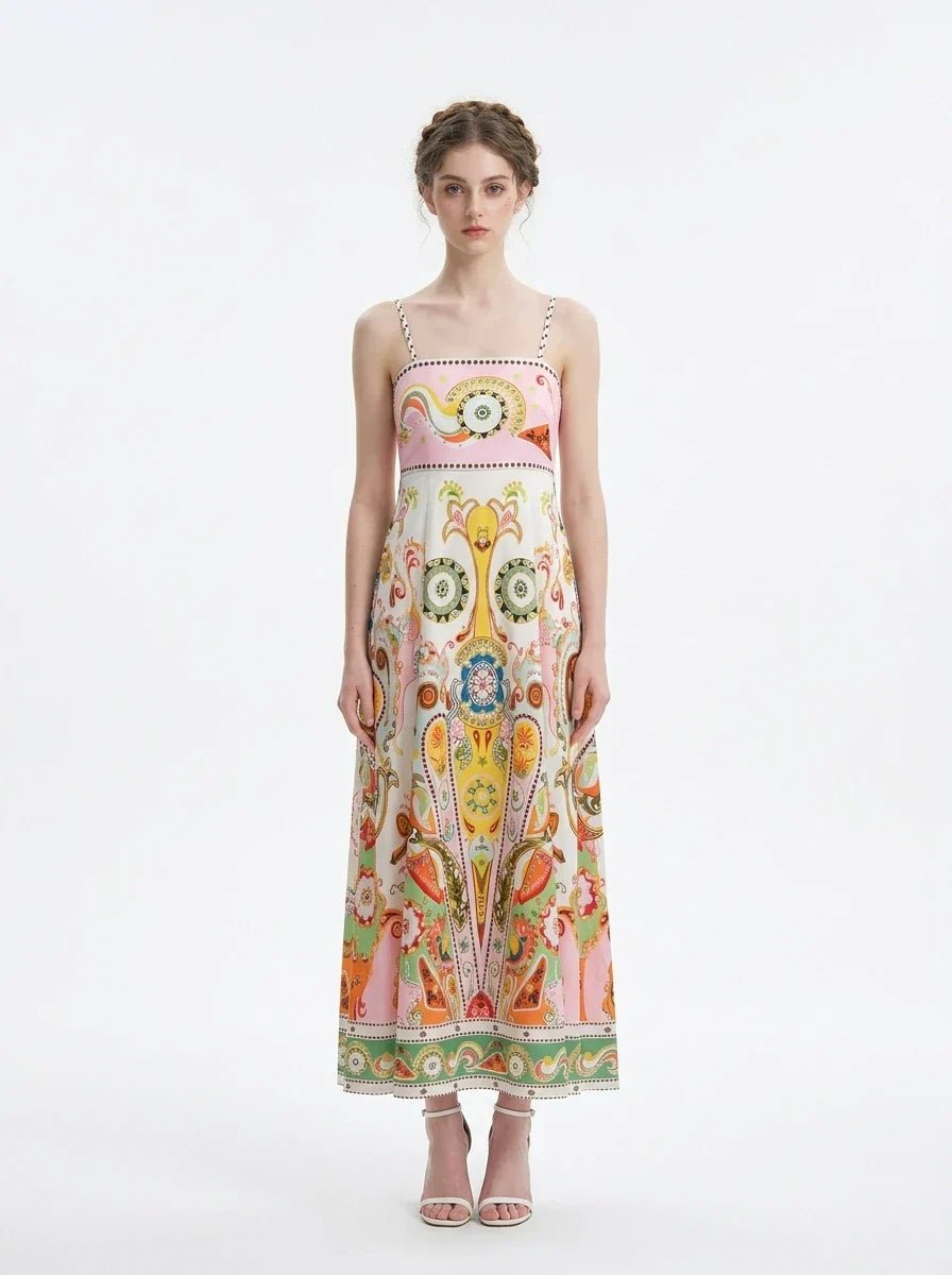 Woman wearing a white maxi dress with a colorful paisley print and pink smocked bodice, standing against a white background.