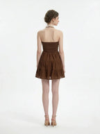 Woman wearing a brown tiered mini halter dress, back view