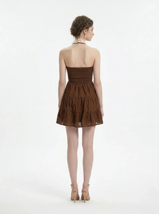 Woman wearing a brown tiered mini halter dress, back view