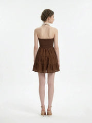 Woman wearing a brown tiered mini halter dress, back view