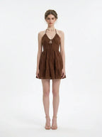 Woman wearing a brown tiered mini halter dress, front view