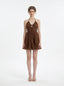 Woman wearing a brown tiered mini halter dress, front view
