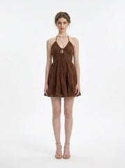 Woman wearing a brown tiered mini halter dress, front view