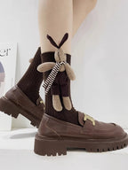 A person wearing brown knee-high ribbed socks with a plush bunny applique and brown chunky sole loafers.