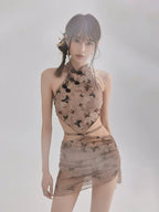 Full body shot of a woman in a sheer butterfly print top and skirt