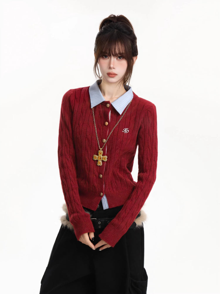 Close-up of the woman's torso showing the red cable knit cardigan with a light blue collared shirt and gold cross necklace.