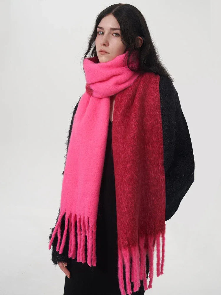 Woman wearing a black sweater and a two-toned pink and red scarf with fringe details.