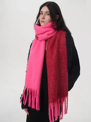 Woman wearing a black sweater and a two-toned pink and red scarf with fringe details.