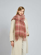 Woman with a hand in her coat pocket, wearing a plaid scarf.