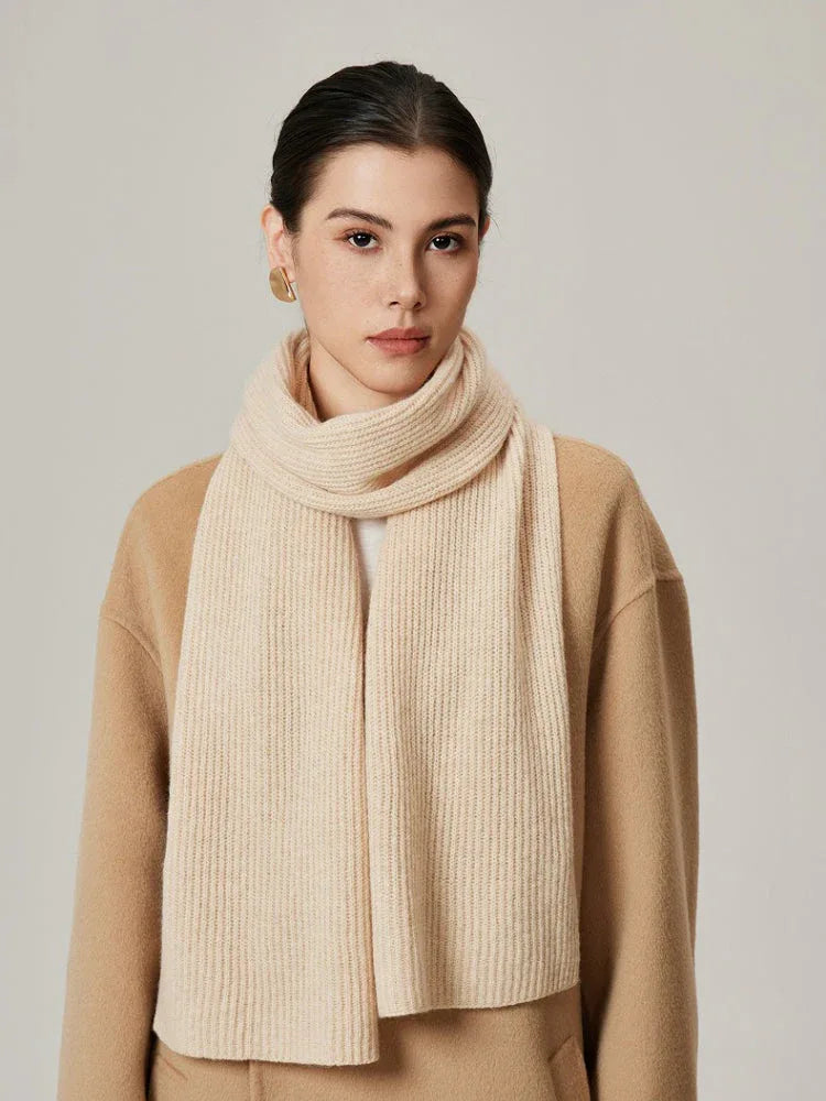 Woman wearing a cream ribbed knit scarf over a beige coat.