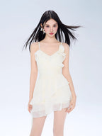Model wearing a white ruffled mini dress with spaghetti straps and a layered skirt