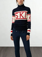 Woman wearing a navy and cream turtleneck ski sweater with red accents, "SKI" graphic, and stars.