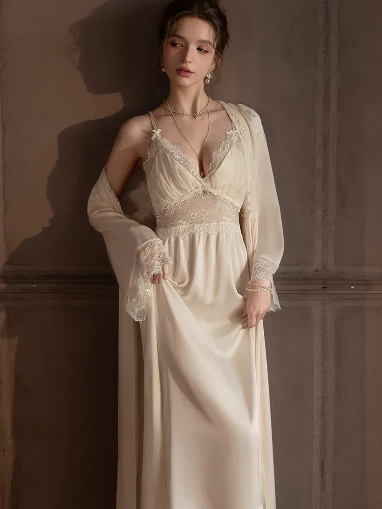 Full body shot of a woman in a cream satin nightgown and robe against a dark background.
