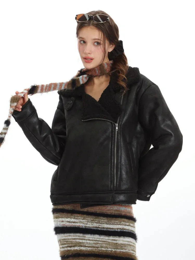 Model wearing a black faux leather jacket, a striped knit maxi skirt, and a multi-colored striped scarf, holding the scarf.