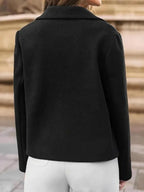 Back view of a woman in a black double-breasted cropped jacket and white pants
