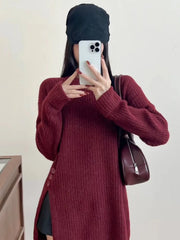 Woman wearing a burgundy ribbed knit longline tunic with side slits and buttons, black shorts, and brown boots, with a black baseball cap on.