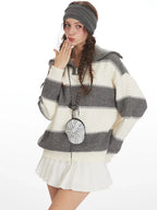 Model wearing a striped knit sweater blowing a kiss