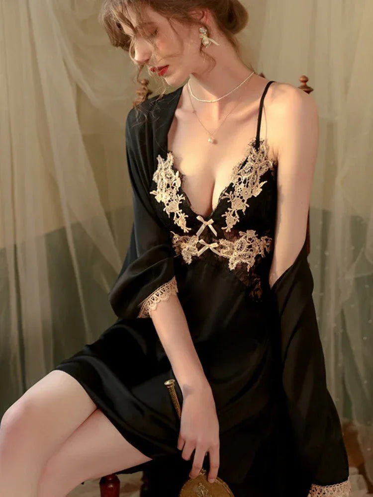 Woman in a black satin slip dress with gold lace detailing and a matching robe, seated in a chair.