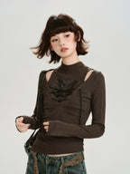 Model wearing a brown long-sleeved ribbed top with cut-out shoulders and a lace-up front, paired with distressed jeans and a crossbody bag.