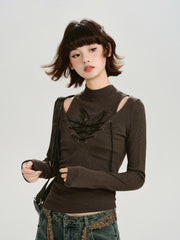 Model wearing a brown long-sleeved ribbed top with cut-out shoulders and a lace-up front, paired with distressed jeans and a crossbody bag.