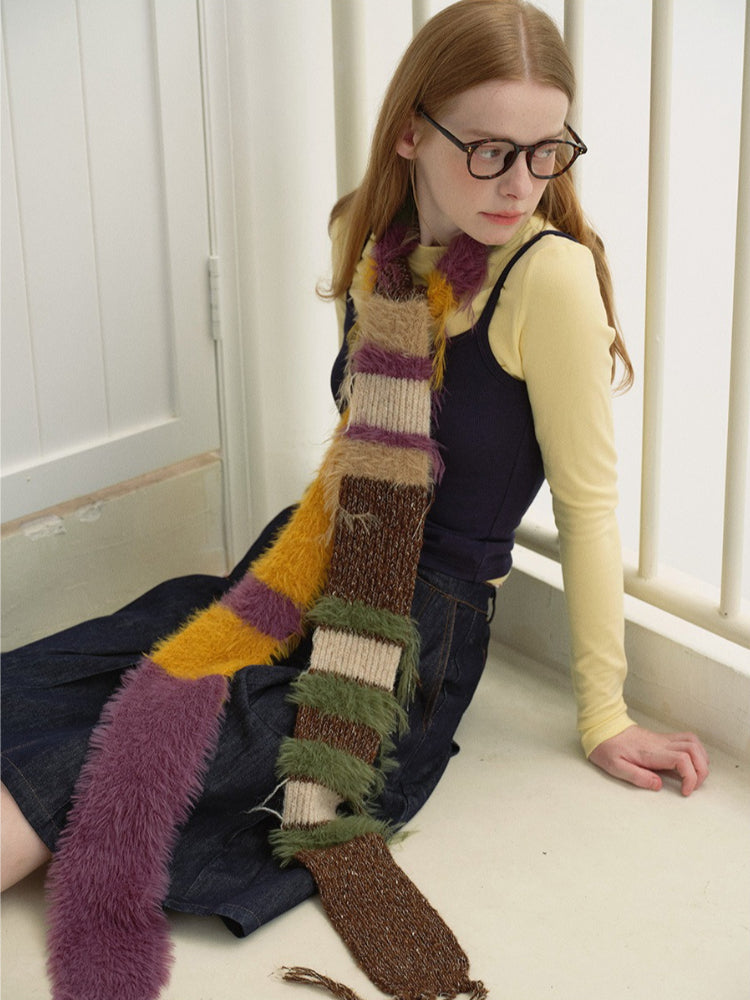 Model wearing a multi-colored striped knit scarf draped around her neck.