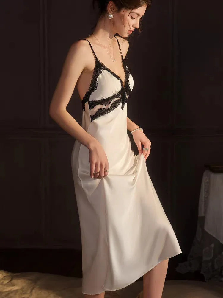 Side view of a woman wearing a white satin slip dress with black lace trim and pearl jewelry.