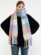 Woman in a black sweater and a pastel plaid scarf draped around her neck.