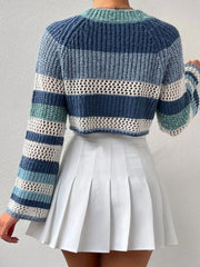 Back view of a woman wearing a blue and white striped crochet knit cropped sweater with bell sleeves, paired with a white pleated mini skirt.