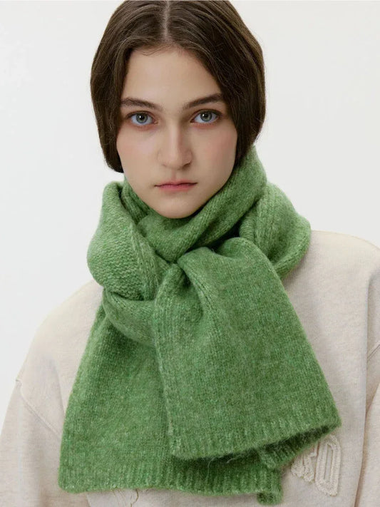 Model wearing a cream sweatshirt and a thick green knit scarf wrapped around her neck, front view.