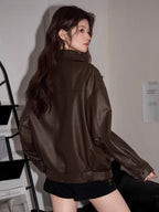 Rear view of a woman wearing a brown faux leather moto jacket.