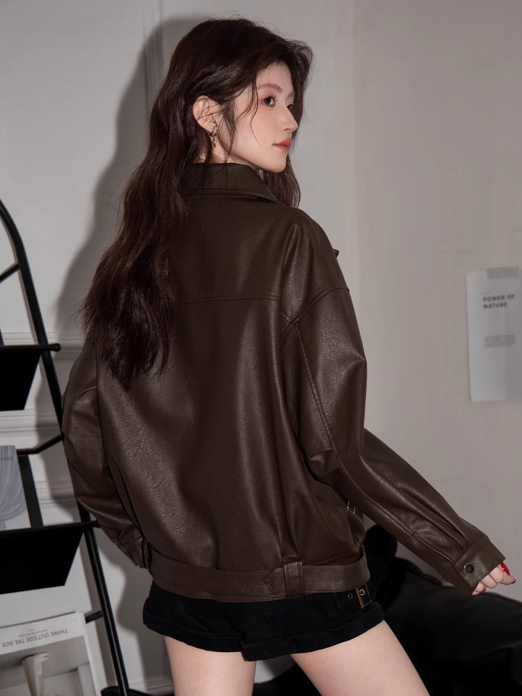 Rear view of a woman wearing a brown faux leather moto jacket.